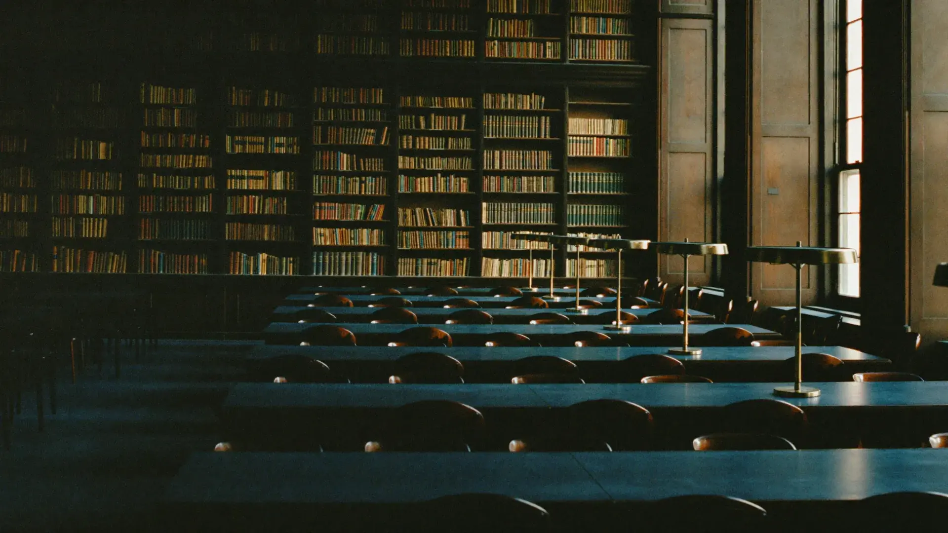 A quiet library reading room with brass lamps in warm afternoon light