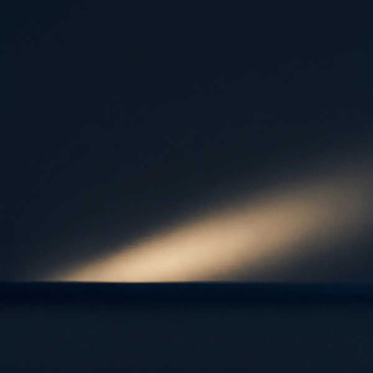 A single warm beam of light rising from a dark navy horizon